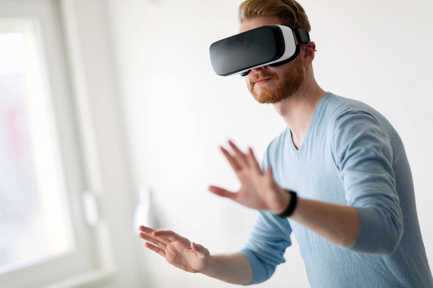 Man wearing virtual reality headset at home trying new experience - Valokuva, kuva