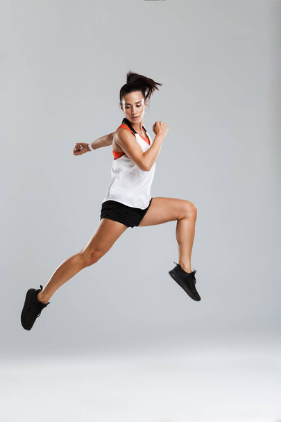 Image of a strong young sports woman jumping make sport exercises isolated indoors. - Photo, image