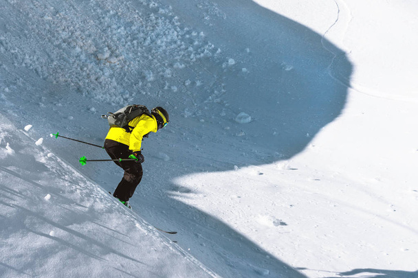 A skier at speed rides on a snowy slope freeride. The concept of winter extreme sports - Photo, Image