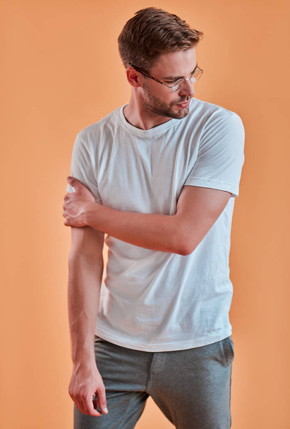 schöner Mann isoliert. stylischer junger Mann mit Brille posiert auf orangefarbenem Hintergrund. - Foto, Bild