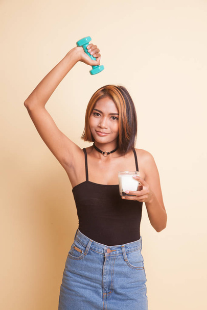 Healthy Asian woman drinking a glass of milk and dumbbell on beige background - Fotografie, Obrázek