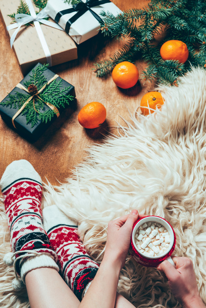 kadın Noel hediyeleri ve mandalina ile arka plan üzerinde kısmi görünümü ile fincan sıcak çikolata ve şekerleme  - Fotoğraf, Görsel