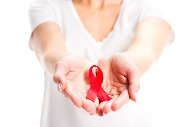cropped image of woman showing red ribbon in hands isolated on white, world aids day concept - Foto, imagen