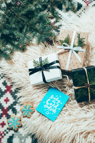 flat lay with pine tree branches, cookies, winter postcards and wrapped christmas presents on woolen backdrop - Фото, зображення
