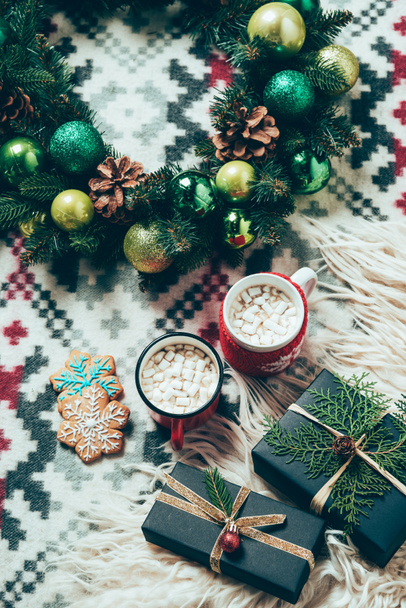 top view of cups of hot drinks with marshmallows, cookies, christmas wreath and gifts on blanket background, christmas breakfast concept - Φωτογραφία, εικόνα