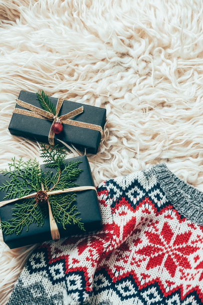 top view of wrapped christmas presents and winter sweater on woolen backdrop - Fotó, kép