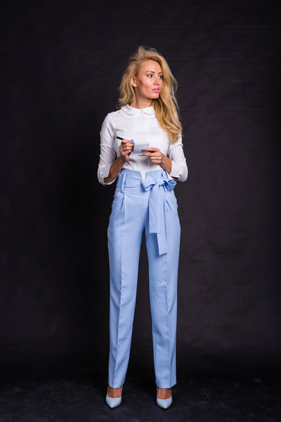 Мода, бізнес і концепція людей мила блондинка в джинсах пише нотатки на наклейках на чорному тлі
 - Фото, зображення