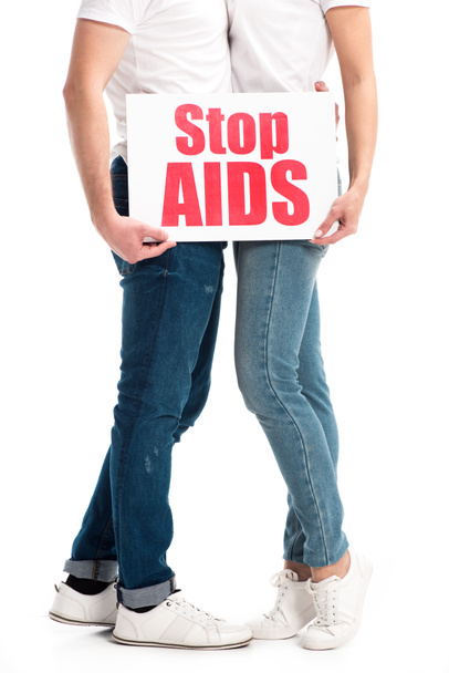 περικομμένη εικόνα ετεροφυλόφιλο ζευγάρι αγκαλιάζει και να κατέχουν κάρτα με stop aids κείμενο απομονωθεί σε λευκό - Φωτογραφία, εικόνα