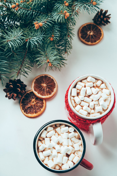top view of cups of hot chocolate with marshmallows and pine tree branches on white surface, christmas breakfast concept - Zdjęcie, obraz