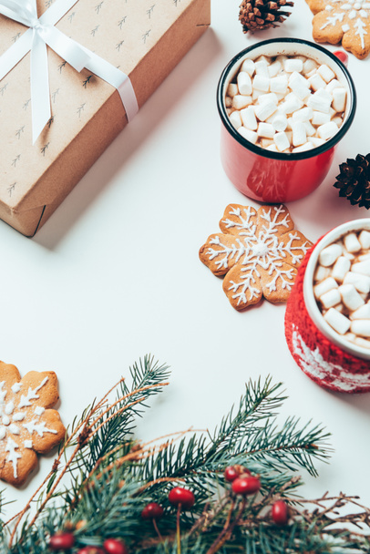 top view of cups of hot chocolate with marshmallows, cookies and christmas present on white tabletop, christmas breakfast concept - 写真・画像