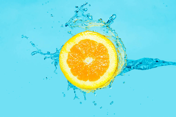 Spruzzi d'acqua in mezza arancia su uno sfondo blu
 - Foto, immagini