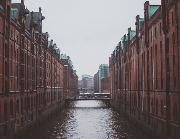 Edificios rojos de ladrillo de almacén sobre el agua del canal oscuro en Hafencity, distrito del puerto en Hamburgo, Alemania. Ambiente místico sombrío
 - Foto, imagen