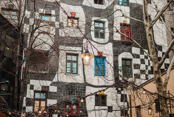 Lighted bulbs against colorful windows of KunstHausWien's monochrome building. Cozy atmosphere in cafe - Foto, afbeelding