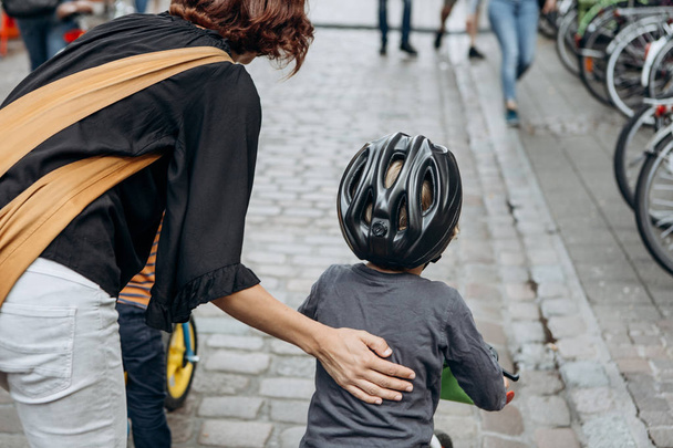 Madre insegna a un bambino ad andare in bicicletta in una strada della città
. - Foto, immagini