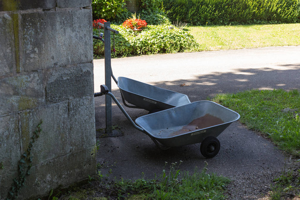 σε ένα νεκροταφείο στη νότια Γερμανία καλοκαιρινή μέρα του Ιουλίου, βλέπετε καροτσάκι, δοχεία, κουβάδες και άλλα εργαλεία που είναι χρήσιμες στο προαύλιο Εκκλησίας - Φωτογραφία, εικόνα
