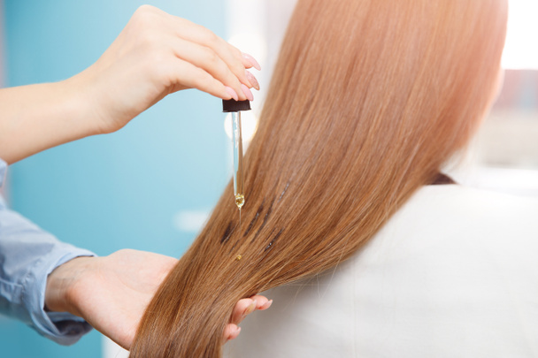 Friseurmeister wendet Öl auf Haarpflege für und Wiederherstellung des Wachstums der Nagelhaut Frau. - Foto, Bild