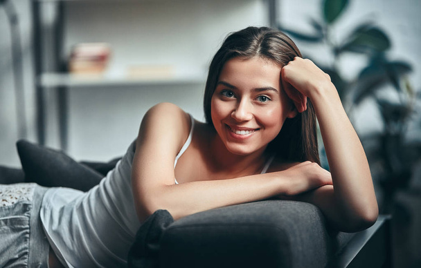 Good morning! Attractive young woman is having rest at home. Girl lying on a sofa. - Foto, afbeelding