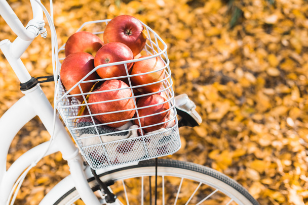 foyer sélectif de vélo avec panier plein de délicieuses pommes rouges à l'extérieur
  - Photo, image