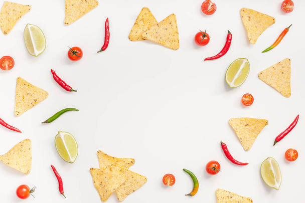 Creative Top view flat lay of fresh mexican food ingredients with tortilla nachos chips garlic pepper lime tomatoes on white table background with copy space. Food preparation cooking concept frame - Φωτογραφία, εικόνα