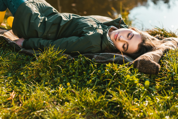 selective focus of young woman sleeping on blanket outdoors  - Фото, зображення