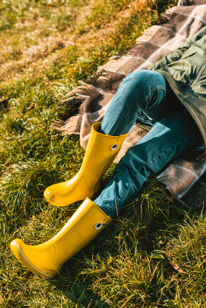 περικομμένη εικόνα της γυναίκας στα κίτρινα λαστιχένια μπότες τοποθέτηση κουβέρτα σε εξωτερικούς χώρους  - Φωτογραφία, εικόνα