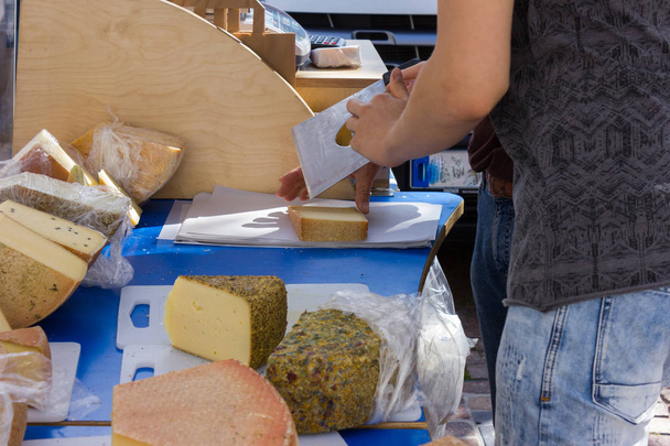 weighing and packing and portioning of some cheese variations on street market in south germany historical city on a summer morning - Photo, Image