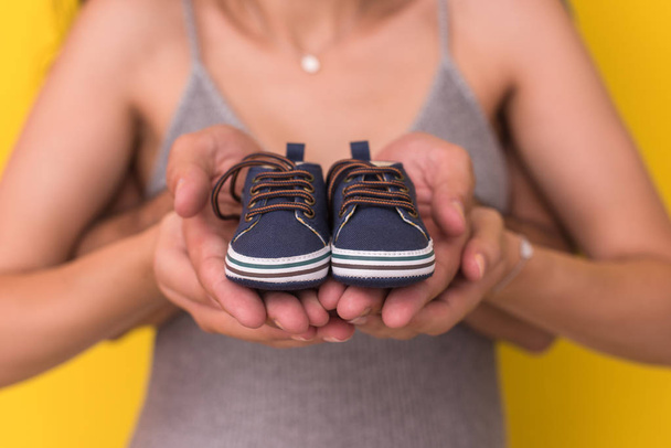young  pregnant couple holding newborn baby shoes  - Фото, изображение