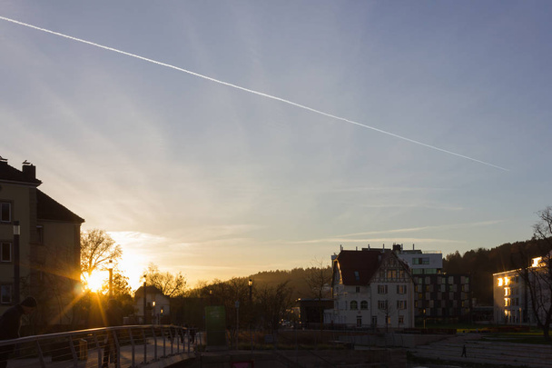 ηλιοβασίλεμα σε ένα βράδυ του Νοεμβρίου σε μια ιστορική πόλη της Νότιας Γερμανίας κοντά σε πόλεις του Μονάχου και Στουτγάρδη με ηλιαχτίδες πολύ σαφείς και να επικεντρωθεί στο μπλε του ουρανού και υπέροχο νερό χρώμα με πάπιες κολύμβηση - Φωτογραφία, εικόνα