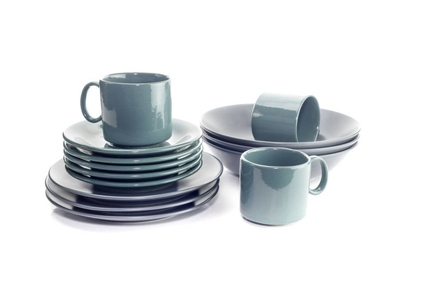 The tableware. New, green cups, saucers and gray plates on white background close-up. - Photo, Image