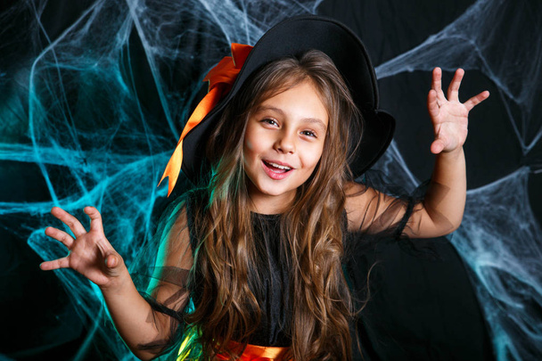 Happy Halloween. Little witch child having fun over spider web and with curved pumpkins background. - Foto, afbeelding