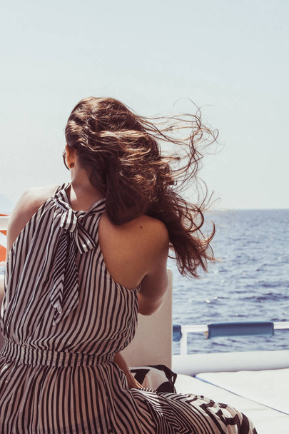 Dívka v černé a bílé šaty v geometrické proužek. Rozpuštěné vlasy. Cesta na lodi na pobřeží Rudého moře v Egyptě. Bruneta na výlet. Módní focení. - Fotografie, Obrázek