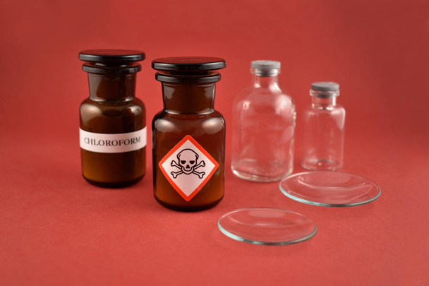 Vial of poison stock images. Vial with warning pictogram stock images. Laboratory accessories images. Vials on a red background. Brown glass containers. Brown chemical glass stock photo - Photo, Image