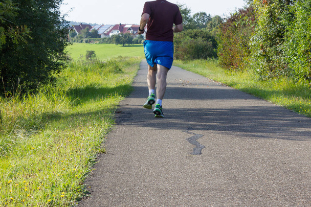 відкритий вправа людини біжить у вересні осінній сезон в Південній Німеччині з зеленій галявині біля і Сонячний погодних умов - Фото, зображення