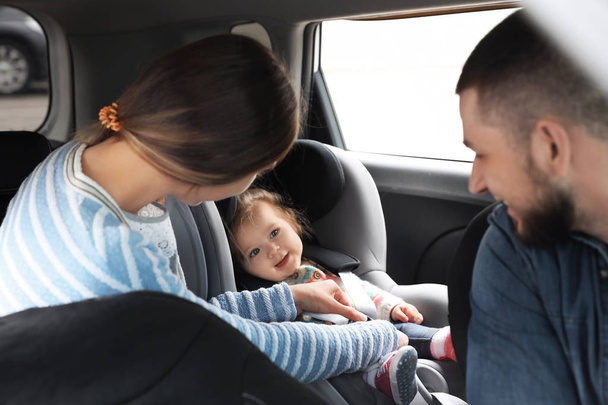 Young parents with baby in safety seat inside car - Valokuva, kuva
