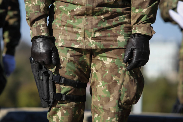 Details zu den Uniformen, Handschuhen und Handfeuerwaffen der Soldaten, die in der Schlange stehen - Foto, Bild