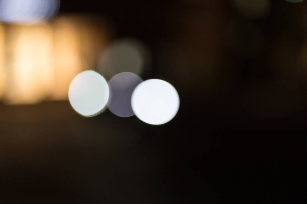 Citylights in der Nacht mit Bokeh-Effekten des vorbeifahrenden Verkehrs und dahinter Schaufenster mit Neonröhren leuchten durch - Foto, Bild