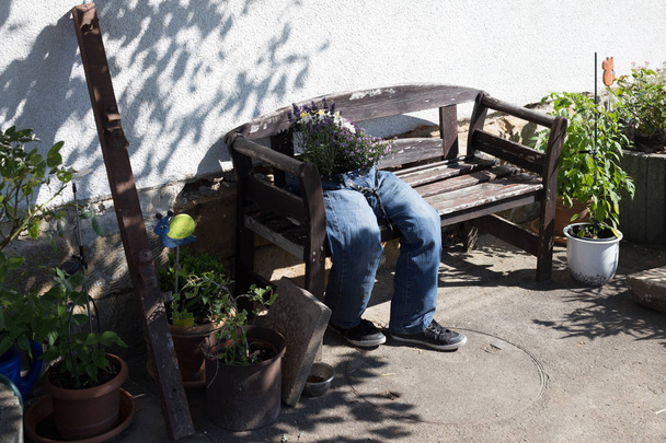 jeans cortados decorados con flores sentadas en un banco de jardín como decoración al aire libre en el campo del sur de Alemania en un día de verano en julio
 - Foto, imagen