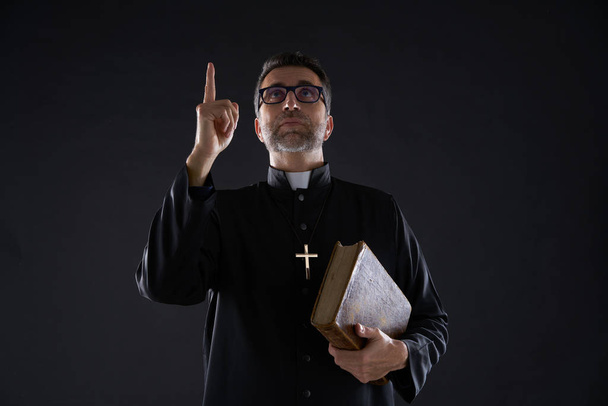 Priest male holding bible pointing finger up to heaven in sky - Photo, Image