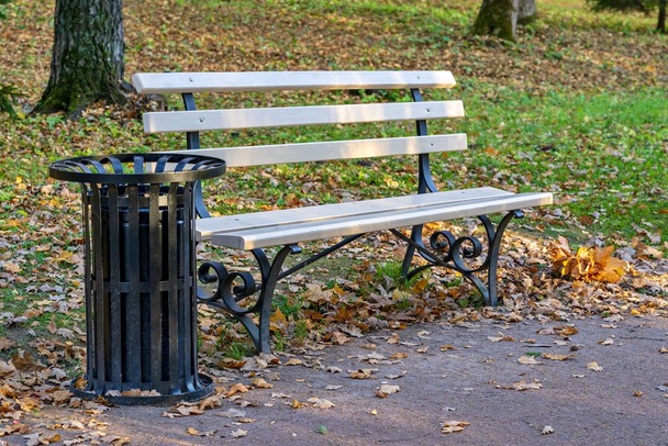 одна скамейка и бак для мусора крупным планом в осеннем парке
 - Фото, изображение