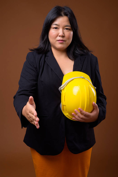 Asian businesswoman holding hardhat and offering handshake - Fotó, kép