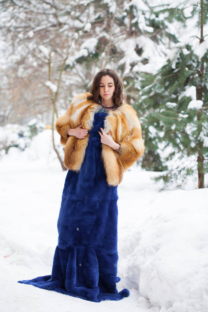 Full length portrait of young beautiful elegant brunette woman wearing fur coat. Fashionable girl walking at the street at winter. - Foto, afbeelding