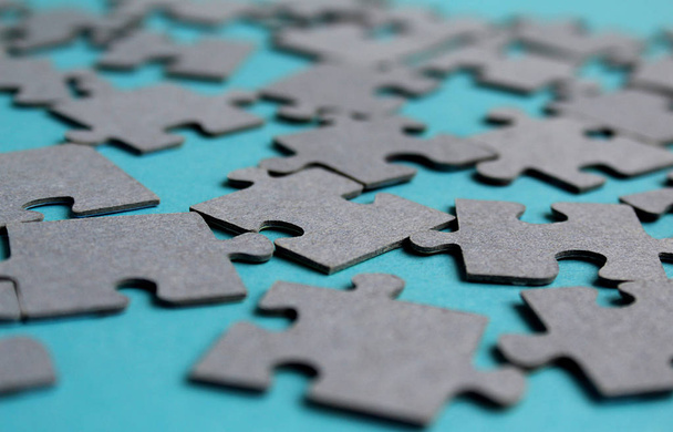 Gray puzzles laid out on the table on a gray background - Foto, afbeelding