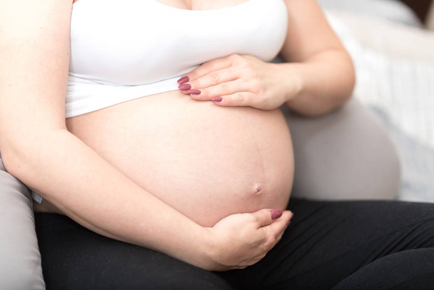 Pregnant woman holding hands on her belly - Fotoğraf, Görsel