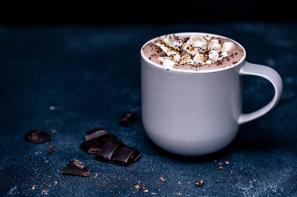 Uma xícara de cacau quente com chocolate e marshmallow na mesa escura
 - Foto, Imagem