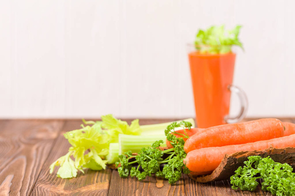 Carrot and celery juice with fresh vegetables on bark plates on wooden background - raw vegetarian vitamin drink for healthy eating concept. Organic food and beverage decorated with parsley leaves. - Fotografie, Obrázek