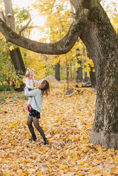 Young mother with beautiful daughter are walking in the park in the golden autumn. Have fun, laugh, take a selfie. - Foto, Imagem