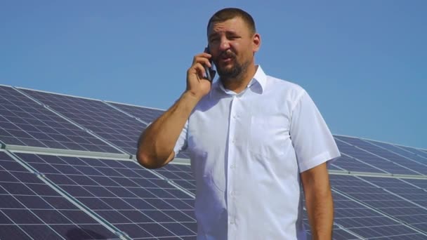 Güneş panelleri arka plan üzerinde telefonda konuşan adam - Video, Çekim