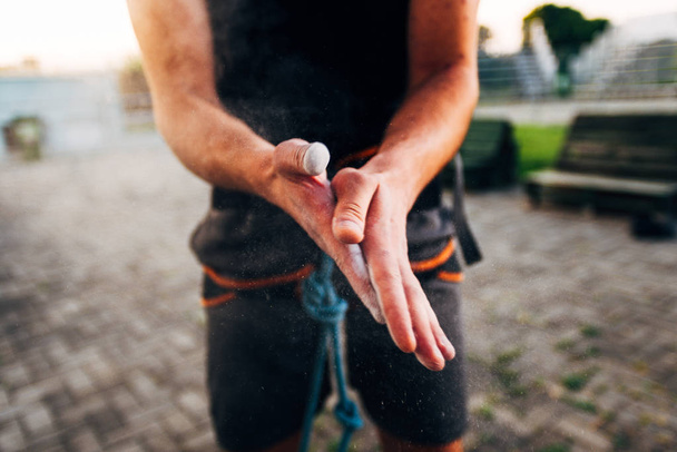 Homme grimpeur enrobant ses mains de magnésium à la craie en poudre et se préparant à grimper
 - Photo, image