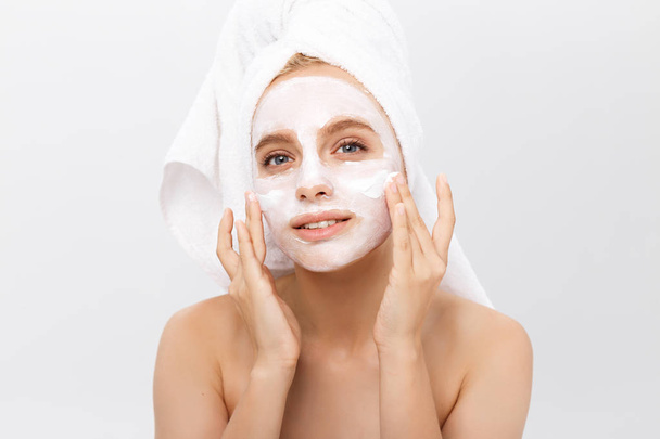 Close-up hermosa mujer aplicando crema cosmética hidratante en la cara sobre fondo claro
. - Foto, imagen