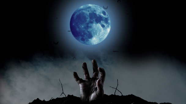 Menselijke hand klimt in de begraafplaats achter een heldere blauwe maan en een blauwe schittert. Zwarte rokerige achtergrond - Video